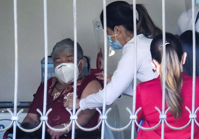 Personal del ministerio de Salud fue registrado este jueves al vacunar a Elizabeth Castillo (i), quien fue la primera persona en ser innoculada contra la covid-19, en San José (Costa Rica). EFE/Jeffrey Arguedas