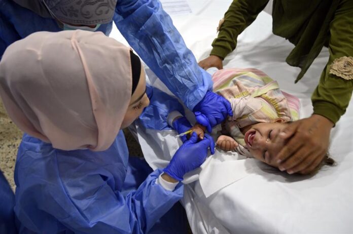 Trabajadores de la salud se preparan para administrar medicamentos a un niño sirio, víctima de un brote de cólera, en un hospital de campaña de la aldea de Bebnine, distrito de Akkar, al norte del Líbano, el 3 de noviembre de 2022. EFE/EPA/WAEL HAMZEH