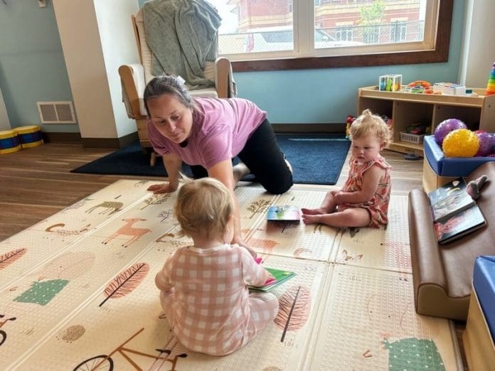 image Una empleada del centro de cuidado infantil Cubby’s Childcare Center in Bridgeport, Virginia Occidental, juega con dos bebés durante el mes de julio. Un grupo bipartidista de legisladores estatales afirma que es hora de replantearse el frágil sistema de cuidado infantil del país. (Foto de Amelia Ferrell Knisely/West Virginia Watch)